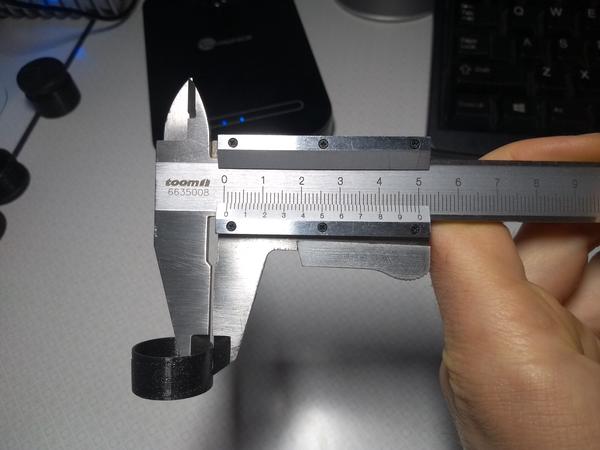 A 3D-printed ring with a thin wall. The wall thickness is being measured with a vernier caliper. The scale shows 0.9mm.