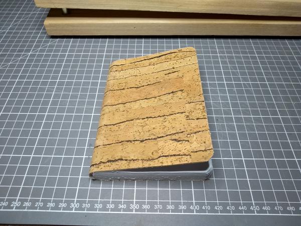 A closed notebook, bound in cork leather.