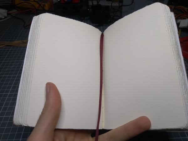 The same notebook, open. The bookmark between the open pages.