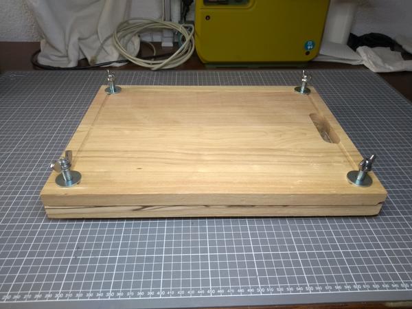A home-made book press, made from two cutting boards and standard hardware (bolts, washers, winged nuts).