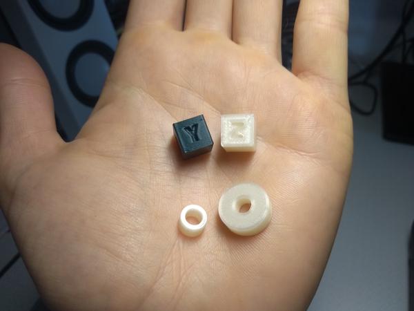 A number of test prints, including two calibration cubes, in a hand.