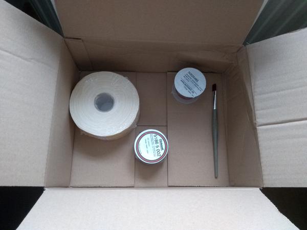 An open cardboard box, with supplies for notebook making.